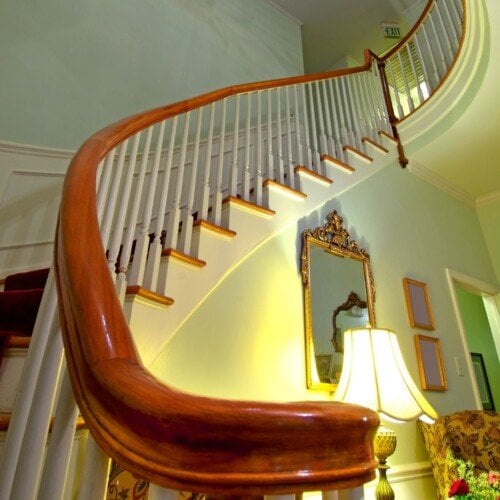 A winding stairway with a shining wooden bannister