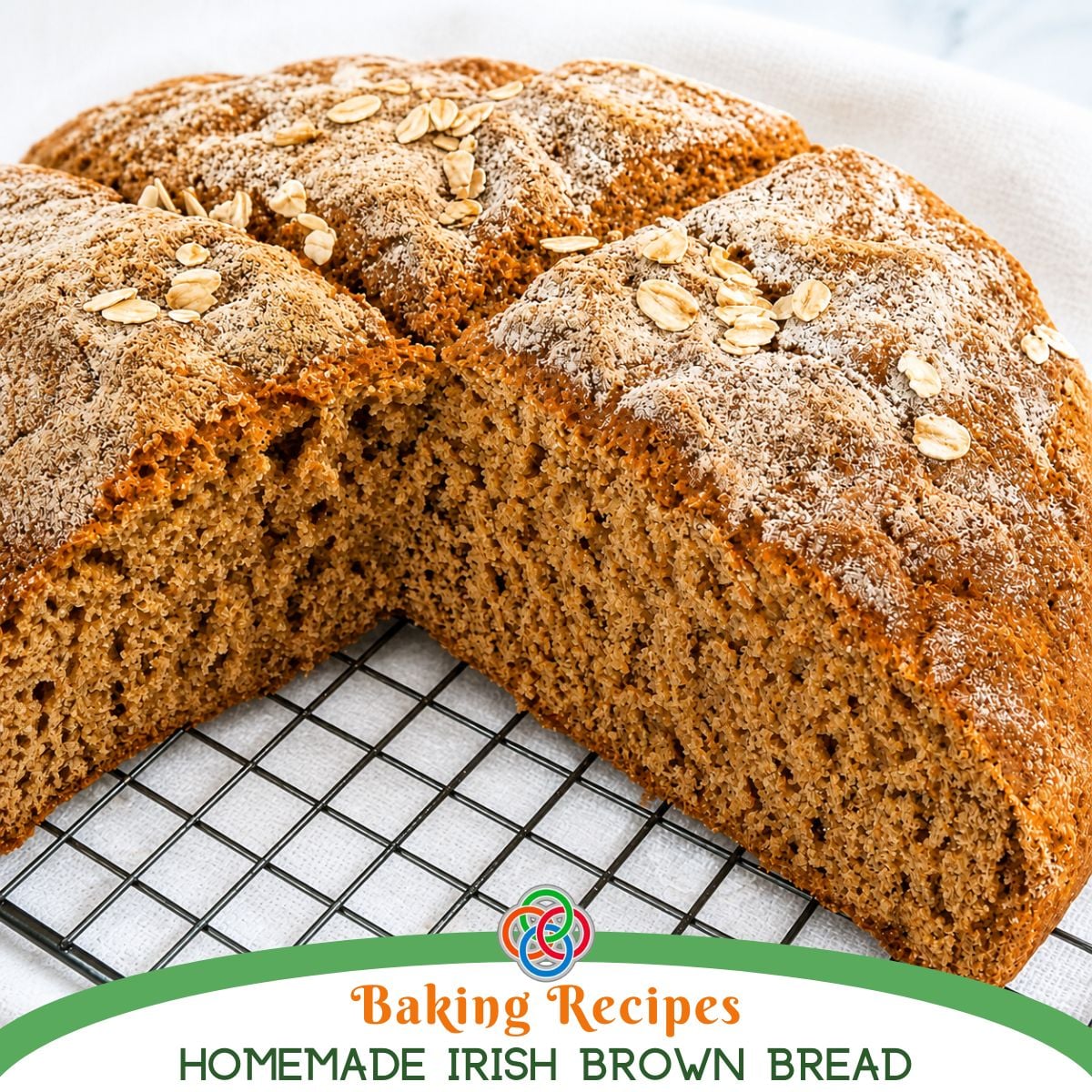 Freshly baked Irish brown bread loaf cut open to show a soft, hearty crumb, topped with oats and resting on a cooling rack over a white cloth.
