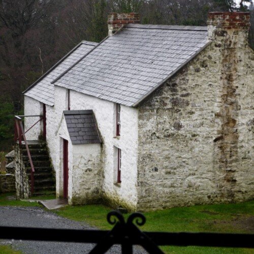 A two storey white stone farmhouse with slate roof as seen from the side
