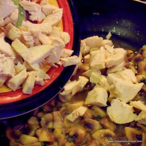 Adding poached chicken to mushrooms and wine in pan | Irish American Mom Adding poached chicken to mushrooms and wine in pan