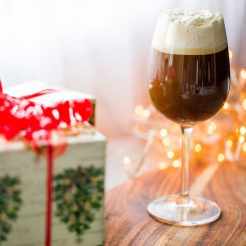An Irish coffee on a table beside a wrapped Christmas gift