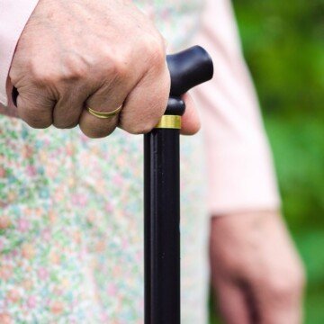 An hold woman holding the handle of a walking cane