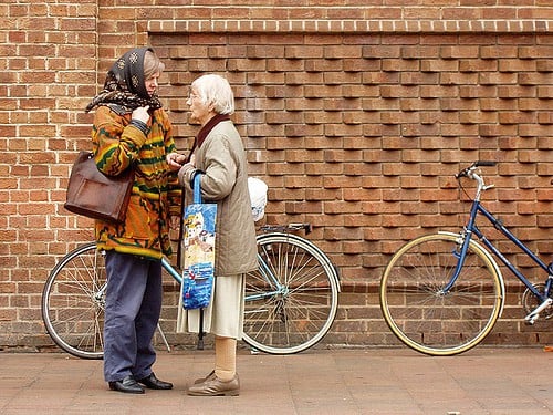 Two women talking beside bicycles by a wall