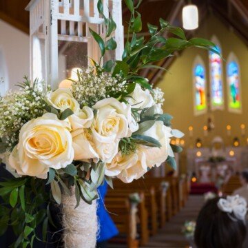 A bouquet of white roses in a vase inside a church