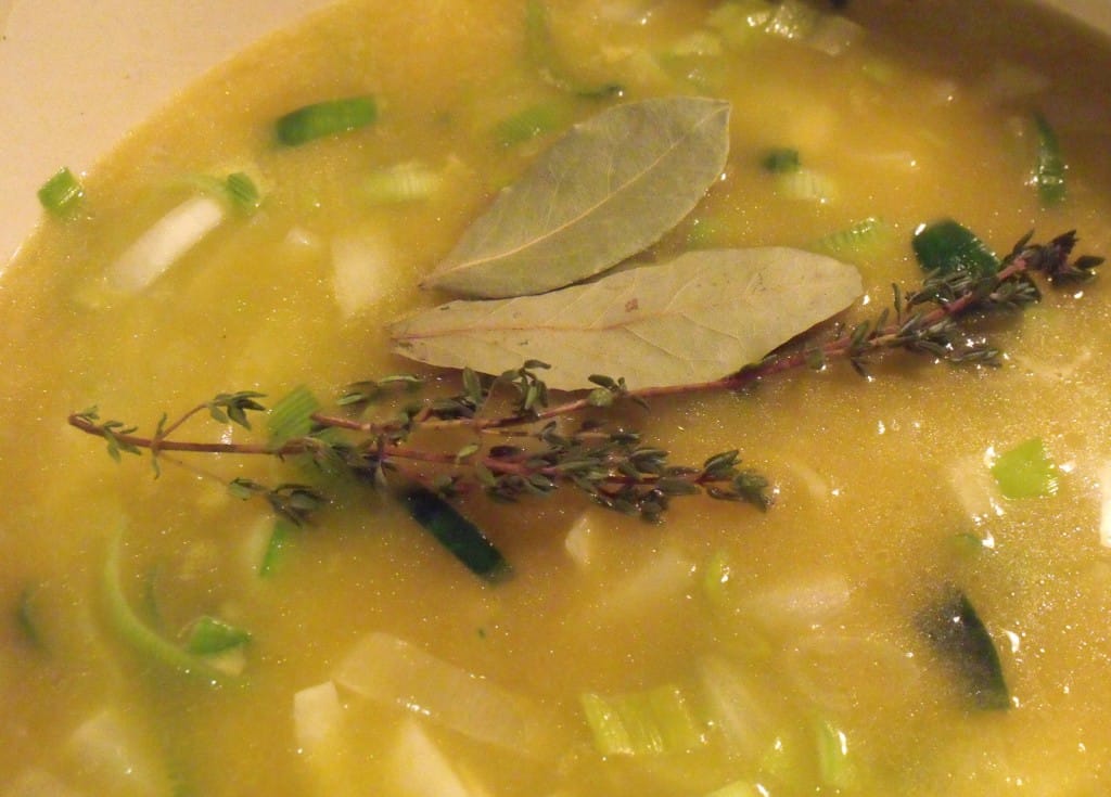 Bay leaf and thyme sprigs in soup Adding fresh sprigs of thyme and bay leaves to a pot of leek and potato soup.
