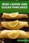 Three rolled Irish pancakes topped with fresh lemon slices, served on a dark surface, showcasing a simple lemon and sugar topping with green text banner.