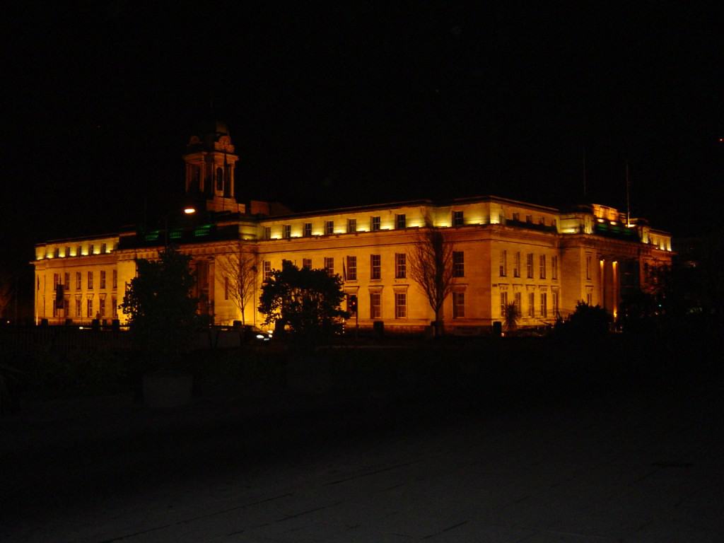 Cork City Hall A large granite building lit up by orange lights in the dark of night