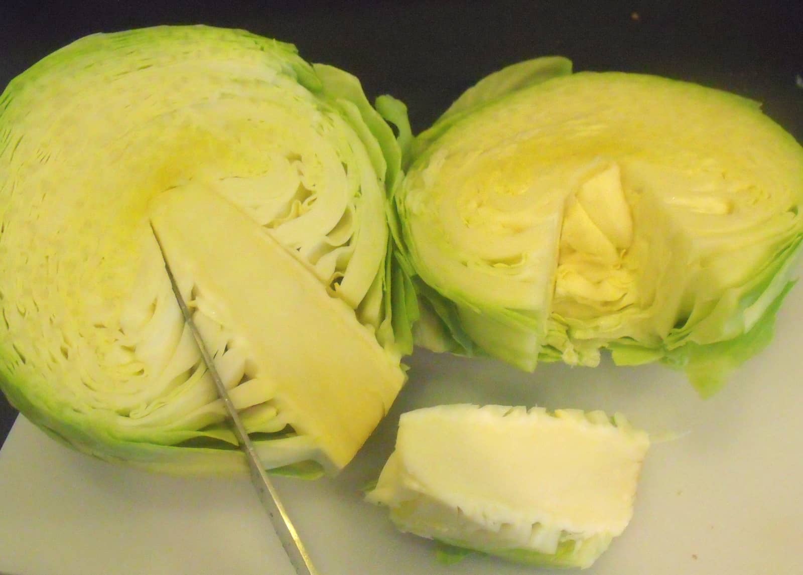 Removing inner stalk from cabbage | Irish American Mom Two halves of a head of green cabbage with the core being cut by a knife