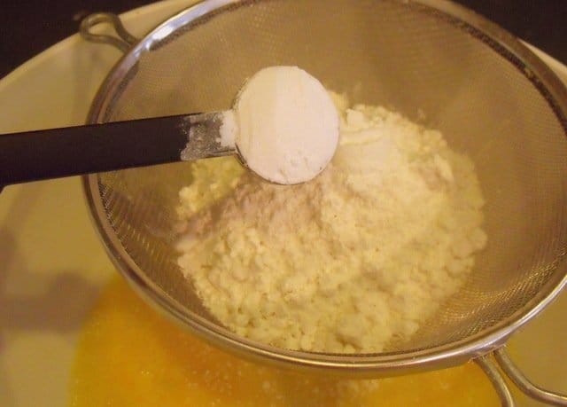 Adding flour and baking powder to beaten egg | Irish American Mom Adding baking powder to flour in a sifter for beer batter