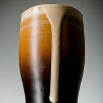 Black porter in a glass with foam streaming down the side of the glass