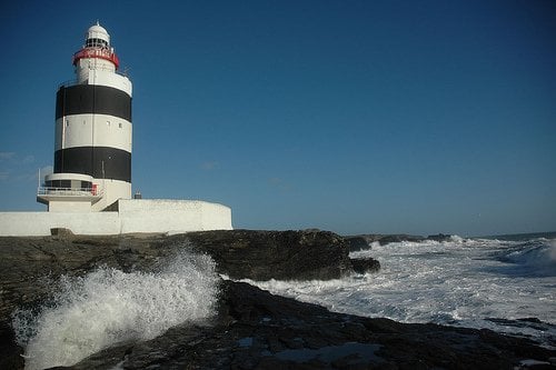 Black and white striped lighthouse by the ocean