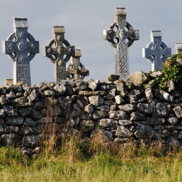 Celtic crosses behind a stone wall beneath a grey sky