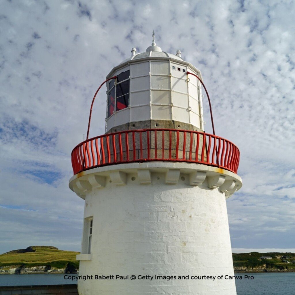 A white lighthouse tower with a red railing around the upper beacon