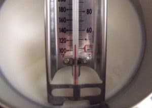 Hot milk with a thermometer in a saucepan