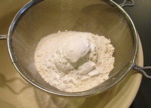 Flour and sugar in a sifter over a bowl