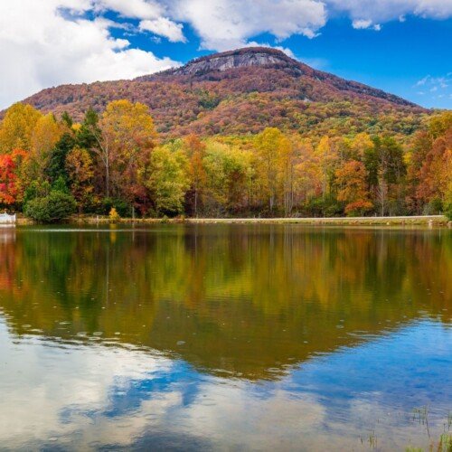 A mountain reflects in a lake with a blue cloudy sky above