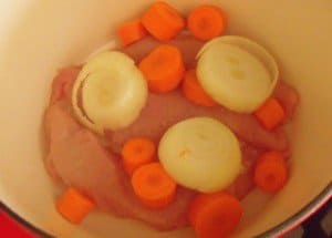 Turkey breasts with carrot and onion at the bottom of a Dutch oven 