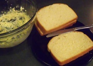 Two sandwiches beside a bowl of garlic butter