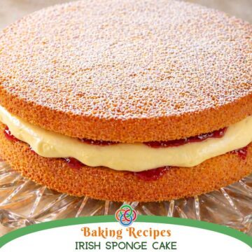 A classic Irish sponge cake dusted with powdered sugar and filled with cream and jam, displayed on a glass cake stand with text banner.