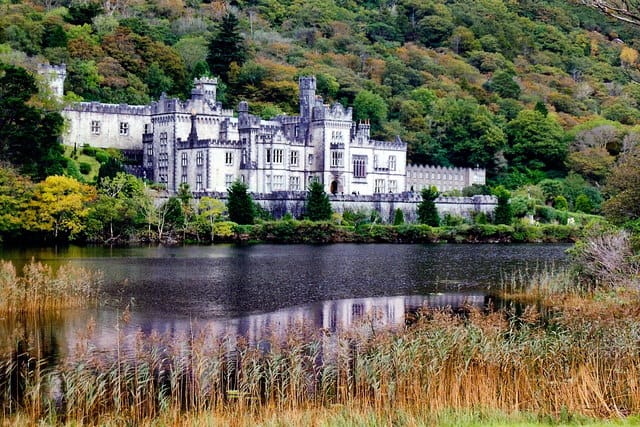 Large castle beside a tree lined hill and lake