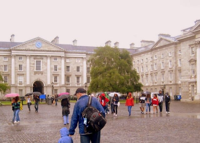 Trinity College, Dublin View of Tourists in Front Square | Irish American Mom A group of people standing in front of a classical stone building in Dublin's Fair City