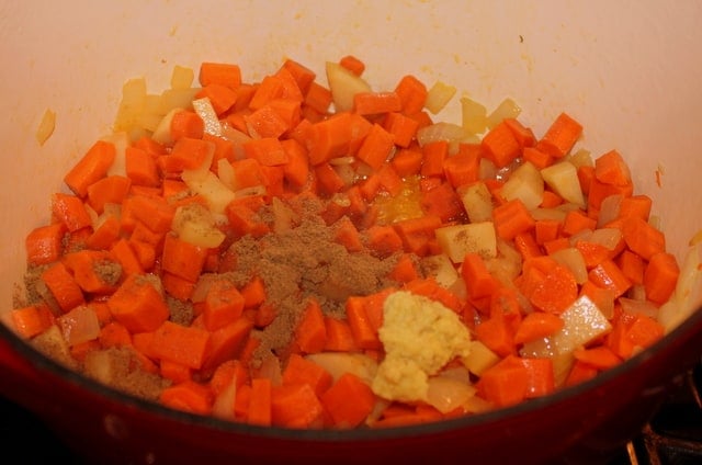 Adding coriander and minced ginger to soup | Irish American Mom Coriander and minced ginger being added to sweated carrots for carrot and coriander soup