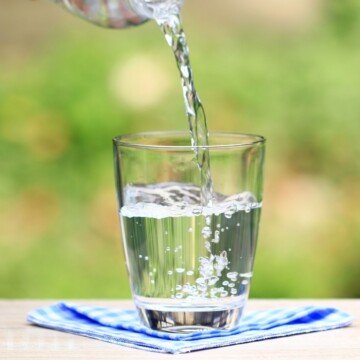 A glass on a blue napkin with water being poured into it
