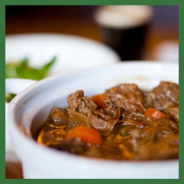 Bowl of stew with a glass of guinness in the background