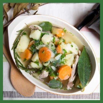 Casserole dish with stew and bay leaves beside a wooden spoon