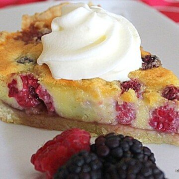 Slice of custard and berry pie with fresh cream and fruit