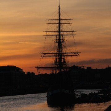 A wooden sail ship on a river at twilight