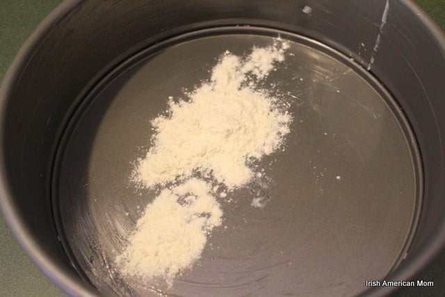 Amount of flour to add to greased baking pan to coat it prior to cooking | Irish American Mom flour sprinkled on a greased pan for lemon blueberry crumb cake