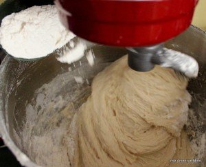 using a mixer to knead potato bread dough while gradually adding flour