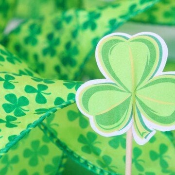 Green shamrock fabric pattern beside a paper shamrock on a stick