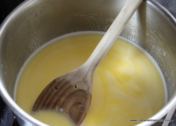 A wooden spoon in custard in a saucepan