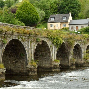 Arched bridge over a river beside two stone cottages