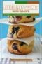 A stack of three golden-brown blueberry scones layered with parchment paper, showing a soft crumb filled with juicy blueberries, styled on a plate with a light blue background and text reading “Blueberry Scones Irish Recipe.”
