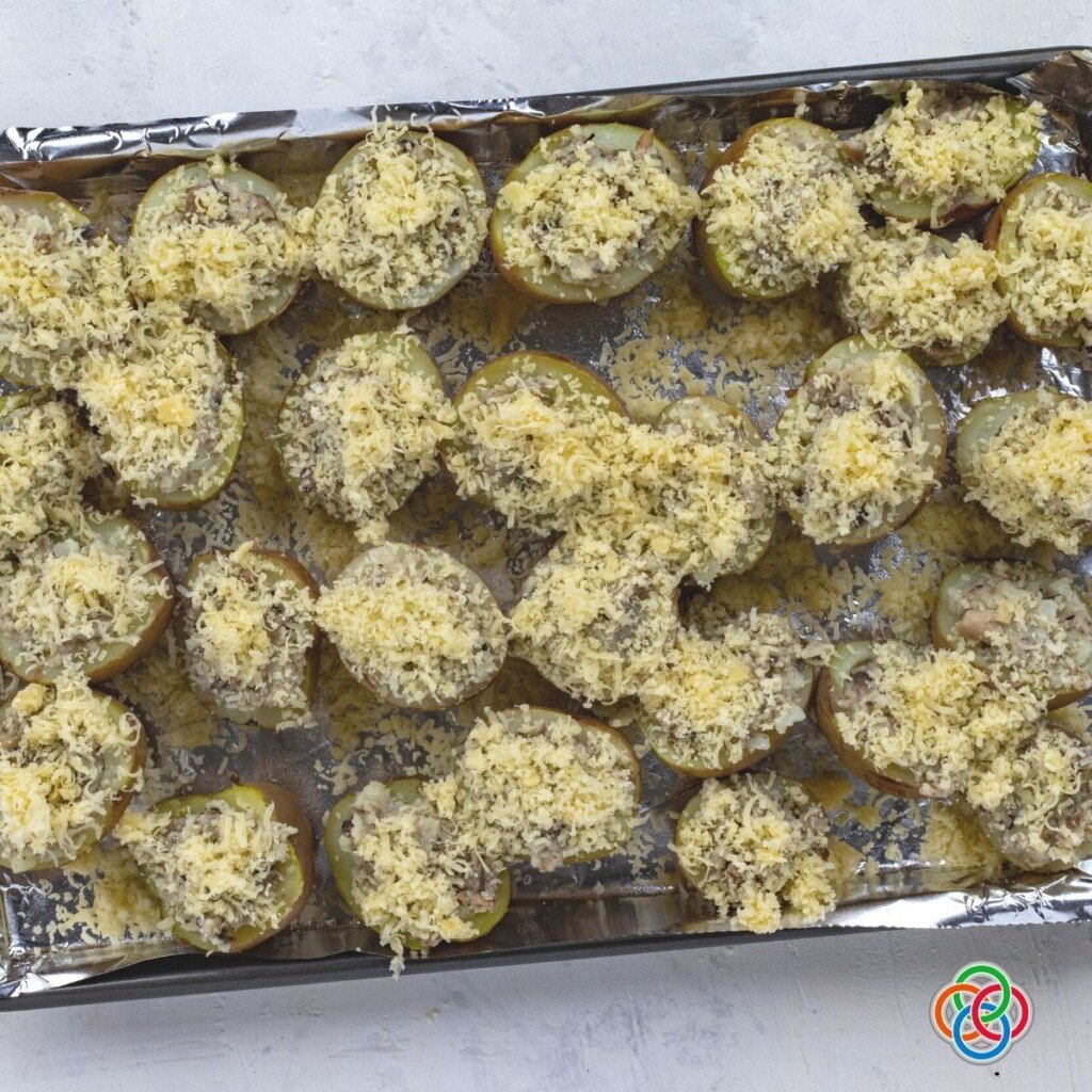 Cheese topped potato appetizers on a baking pan before cookingappetizer | Irish American Mom Grated cheese on stuffed potato shells