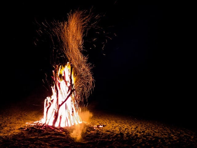 Bonfire sending sparks into a black sky