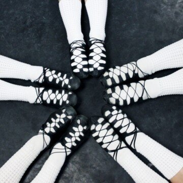 Five pairs of legs with white socks and Irish soft dance shoes in a circle