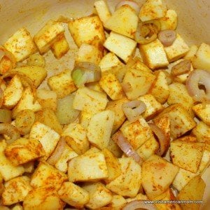 Parsnips and shallots sweating with curry powder in a Dutch oven for parsnip and apple soup