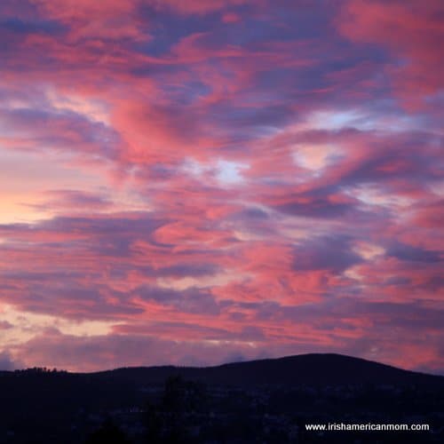 A sunset over a mountain creating a red and purple sky