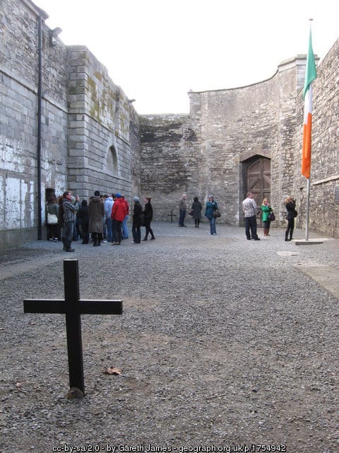 Kilmainham Jail | Irish American Mom People in a yard with a cross and flag