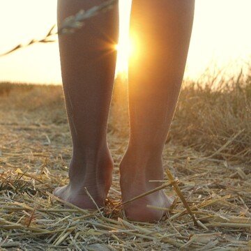 A woman walking barefoot in a field of straw