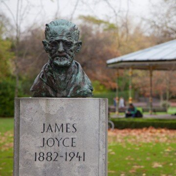 Sculptured bust of a man on a pedestal in a park near a band stand