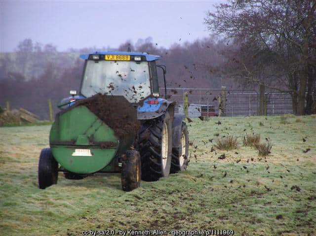 A tractor pulling a dung spreader | Irish American Mom Spreading manure with a tractor in a field