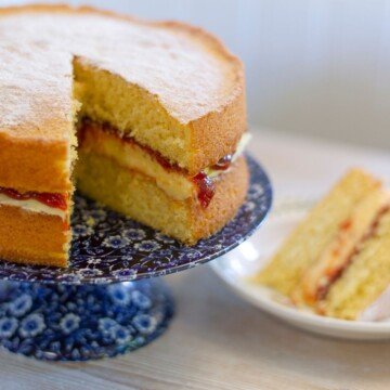 Cream sponge cake on a stand with a slice removed