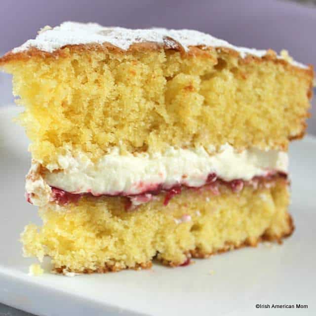 victoria-sponge-sandwich-with-jam-and-cream-using-a-traditional-irish-or-english-recipe | Irish American Mom A slice of Vicotria sponge sandwich with jam and cream on a white plate