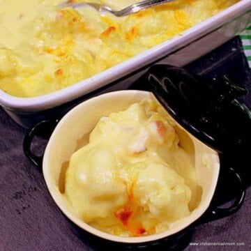 Cauliflower cheese in a small bowl beside a casserole