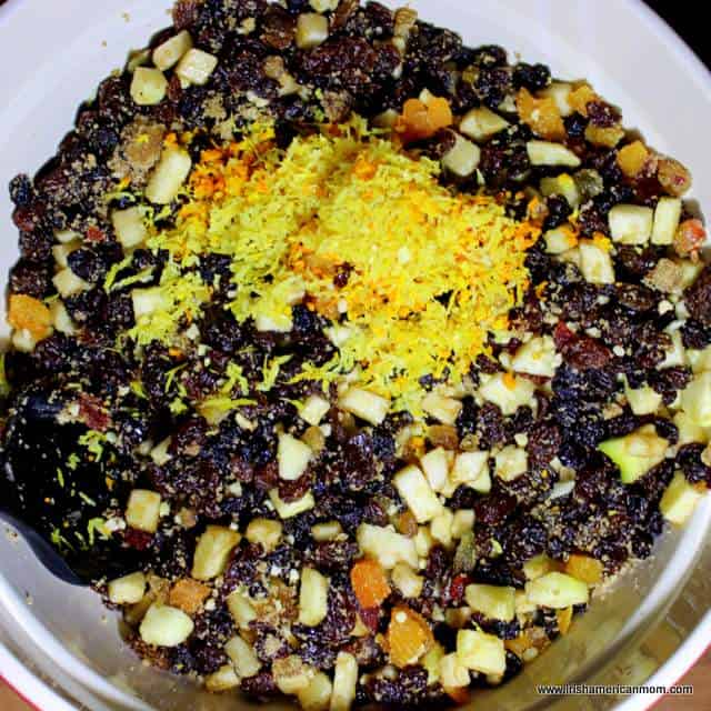 Adding grated lemon and orange peel or rind to mincemeat | Irish American Mom Dried fruits and citrus zest in a bowl.